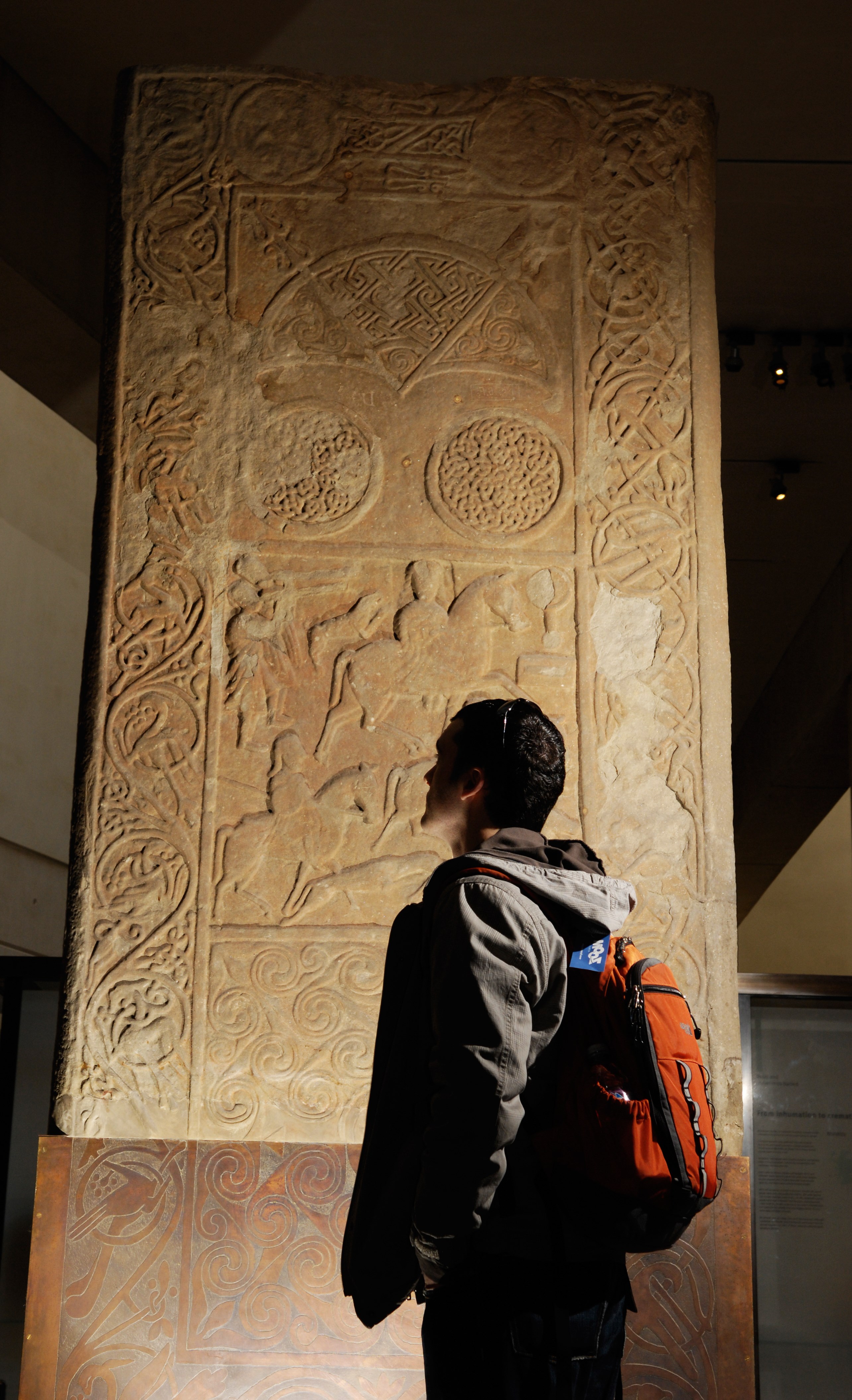 A visitor admires the Hilton of Cadboll stone, on display in Level -1 in the Early People gallery.