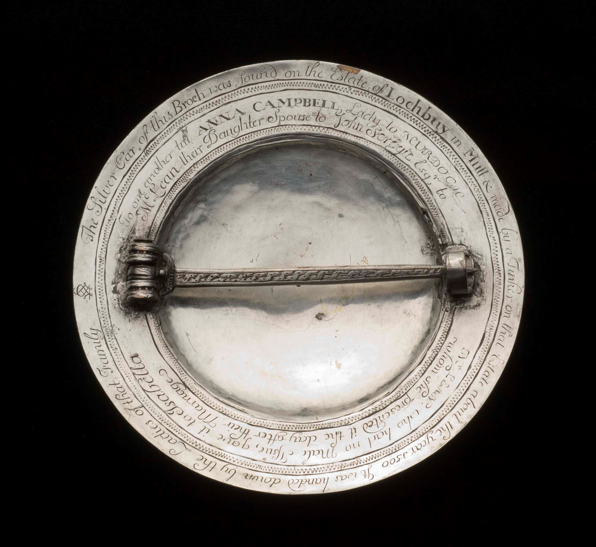 Rear of a circular silver brooch with a pin across.