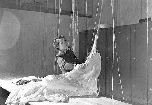 A woman packing up a parachute in a store