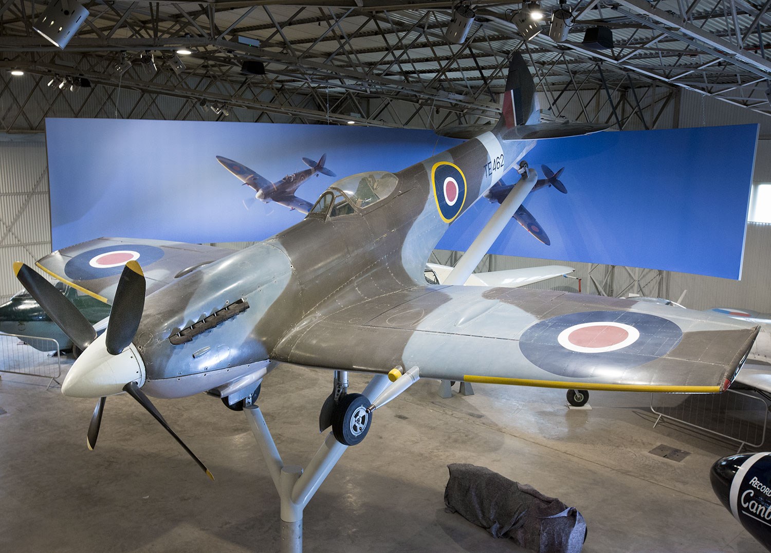 Supermarine Spitfire on display at the National Museum of Flight. In the background is a curved picture with two spitfires flying.