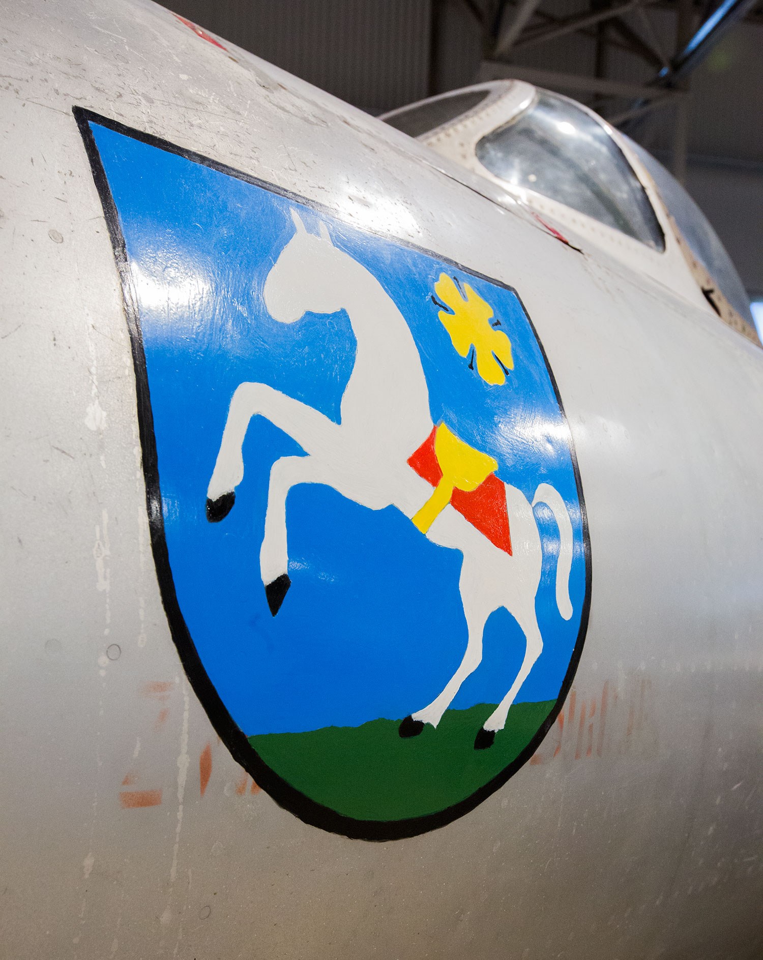 Crest of the city of Ostrava painted on the nose of the Aero S-103 aircraft. The crest has a blue background with a white horse and yellow flower.