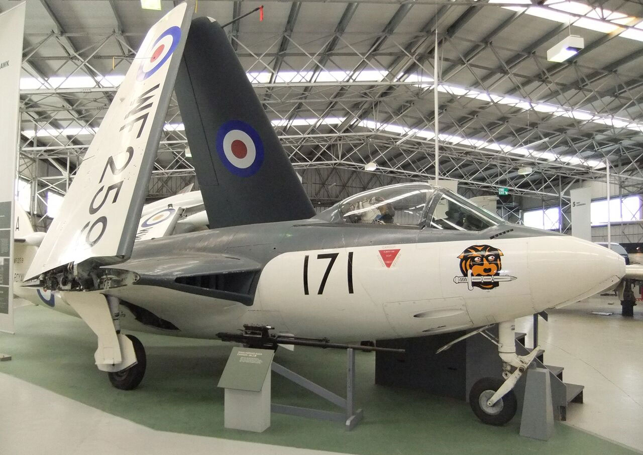The Hawker Sea Hawk aircraft parked in a large aviation hangar. Its wings are folded for easier storage.