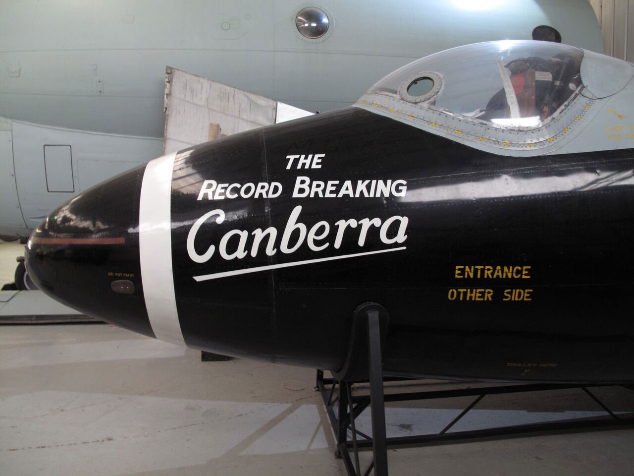 The nose section of a black Canberra aircraft. The side of the aircraft reads 'The record-breaking Canberra, entrance other side.'