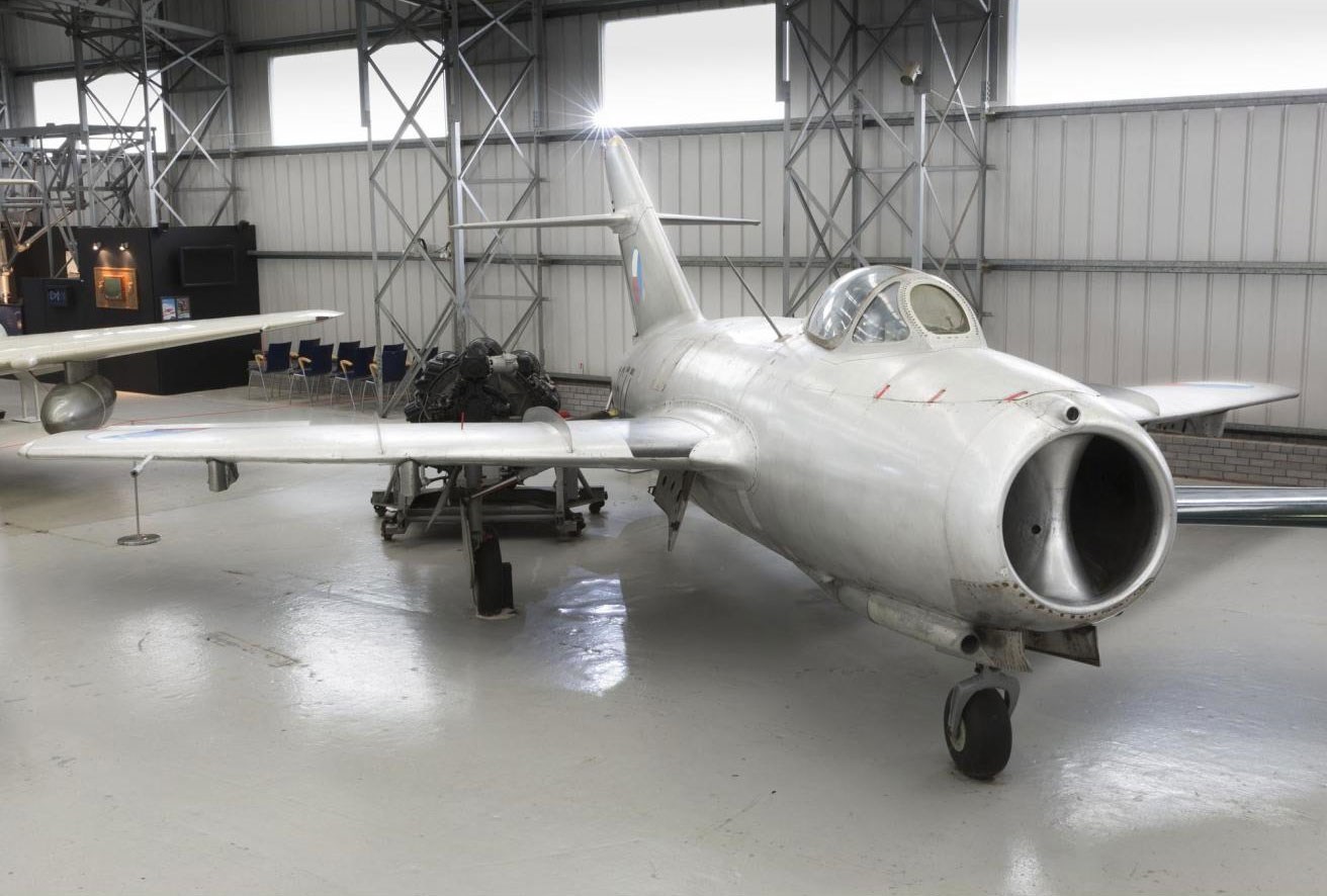 A grey Aero S-103 aircraft parked in a large hangar.