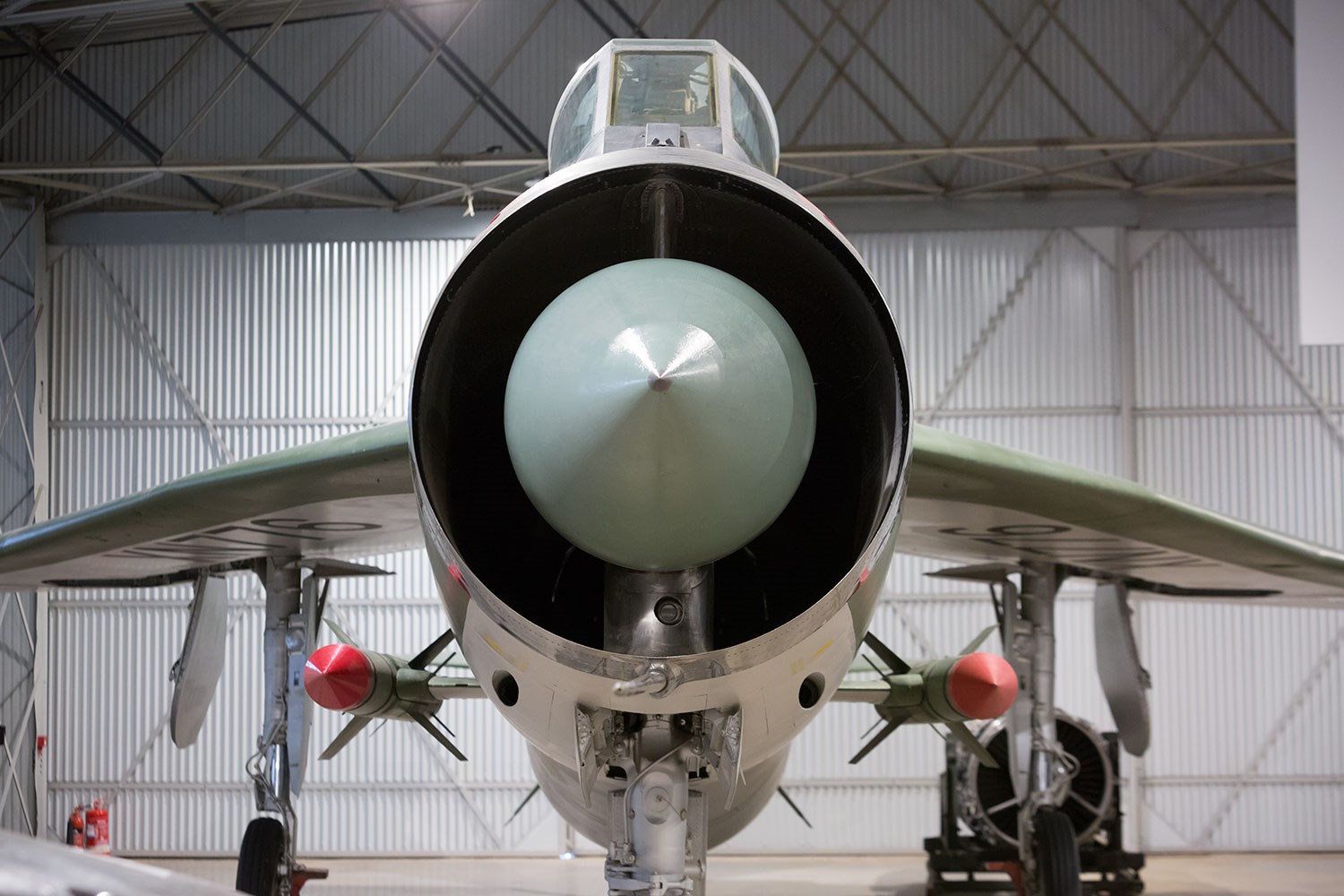 The nose of a green English Electric Lightning aircraft with a missile on either side.