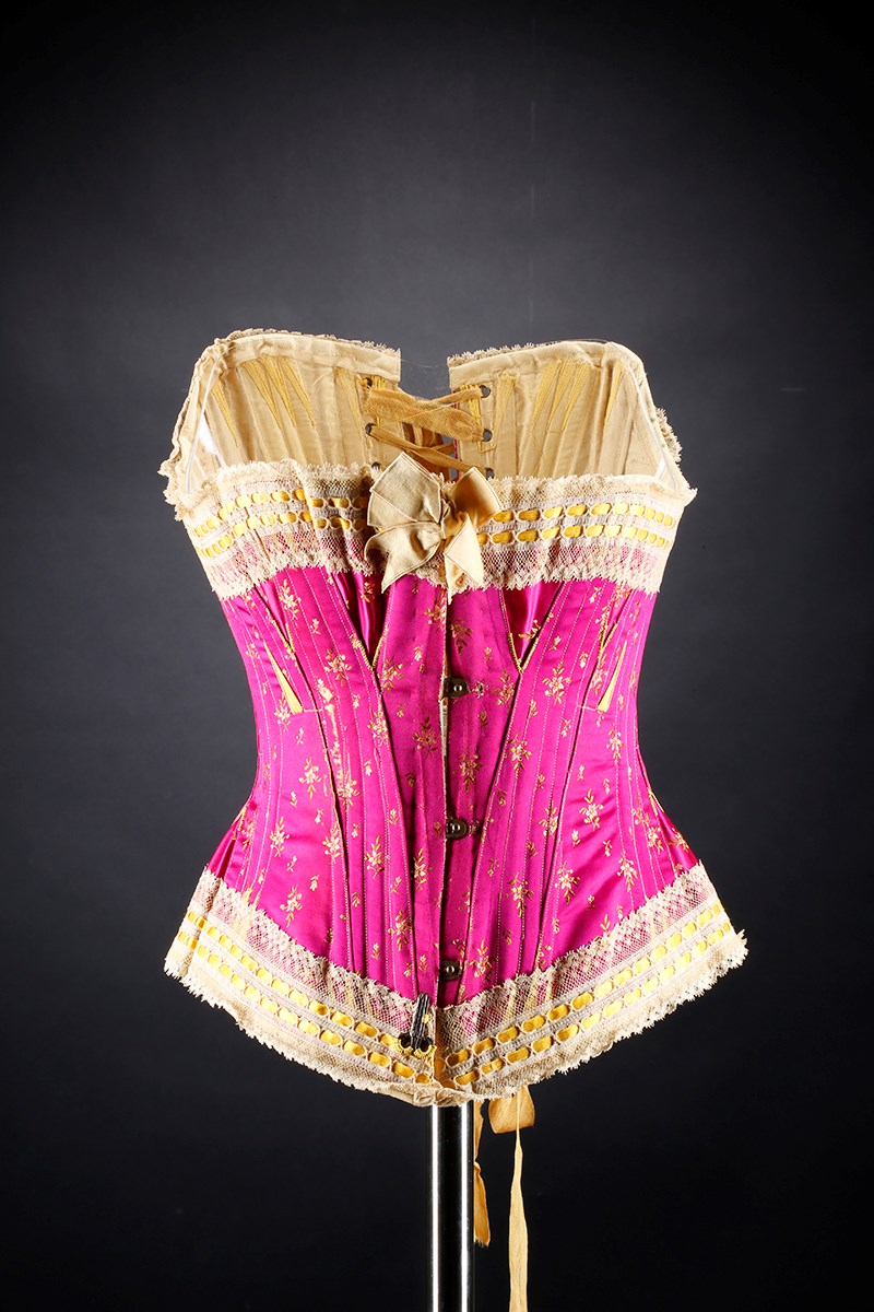 A pink corset with cream and gold lace trim