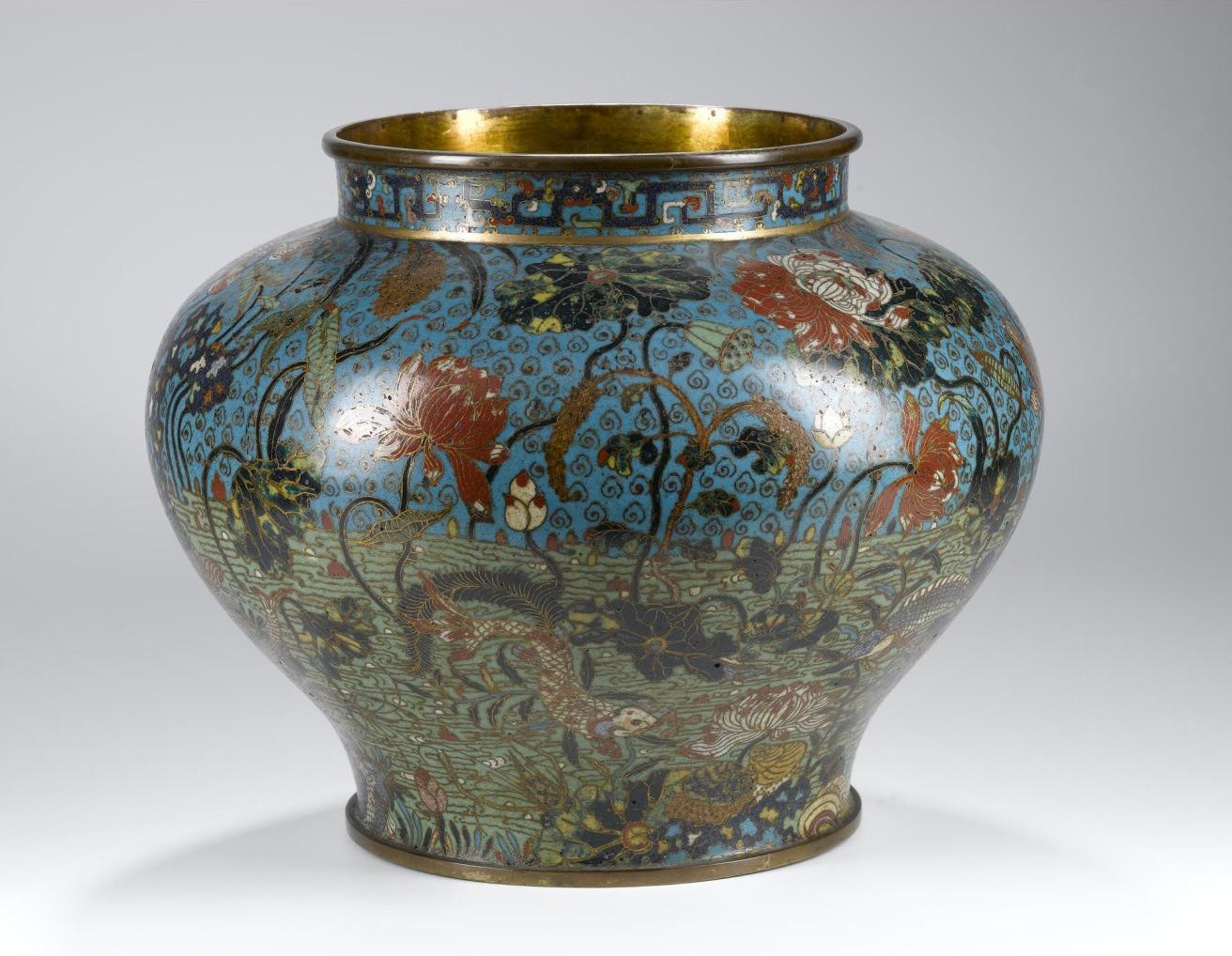 Vase of cloisonne enamel on copper, in colours with fishes among lotus and other aquatic plants, and border of interlocking dragon strapwork design round neck, probable original lid now missing: China, Ming dynasty, 16th century.