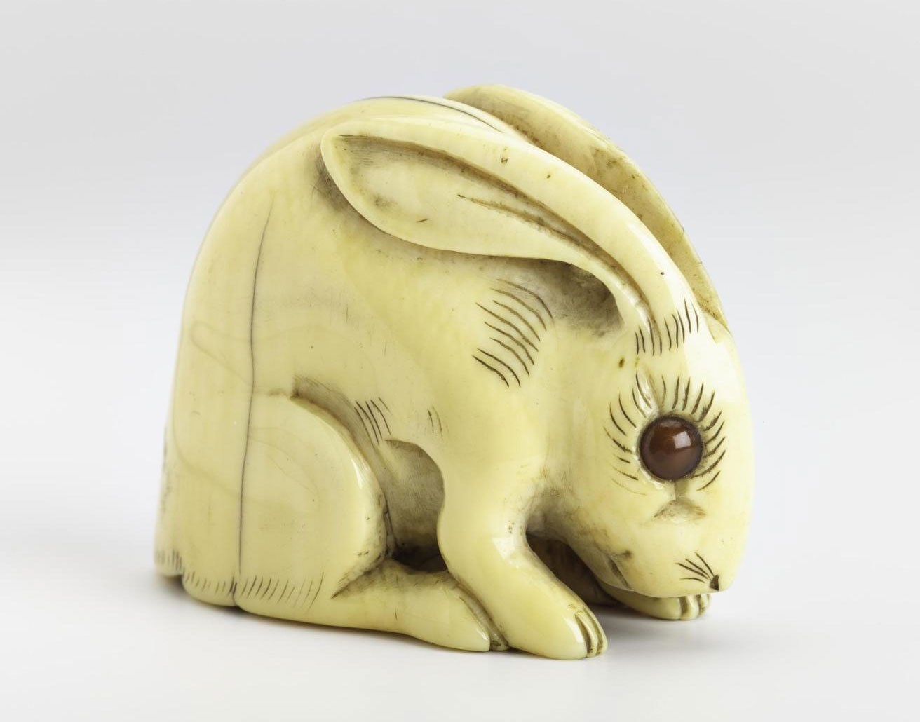 Netsuke of carved ivory, a hare, signed: Japan, by Tomotada.