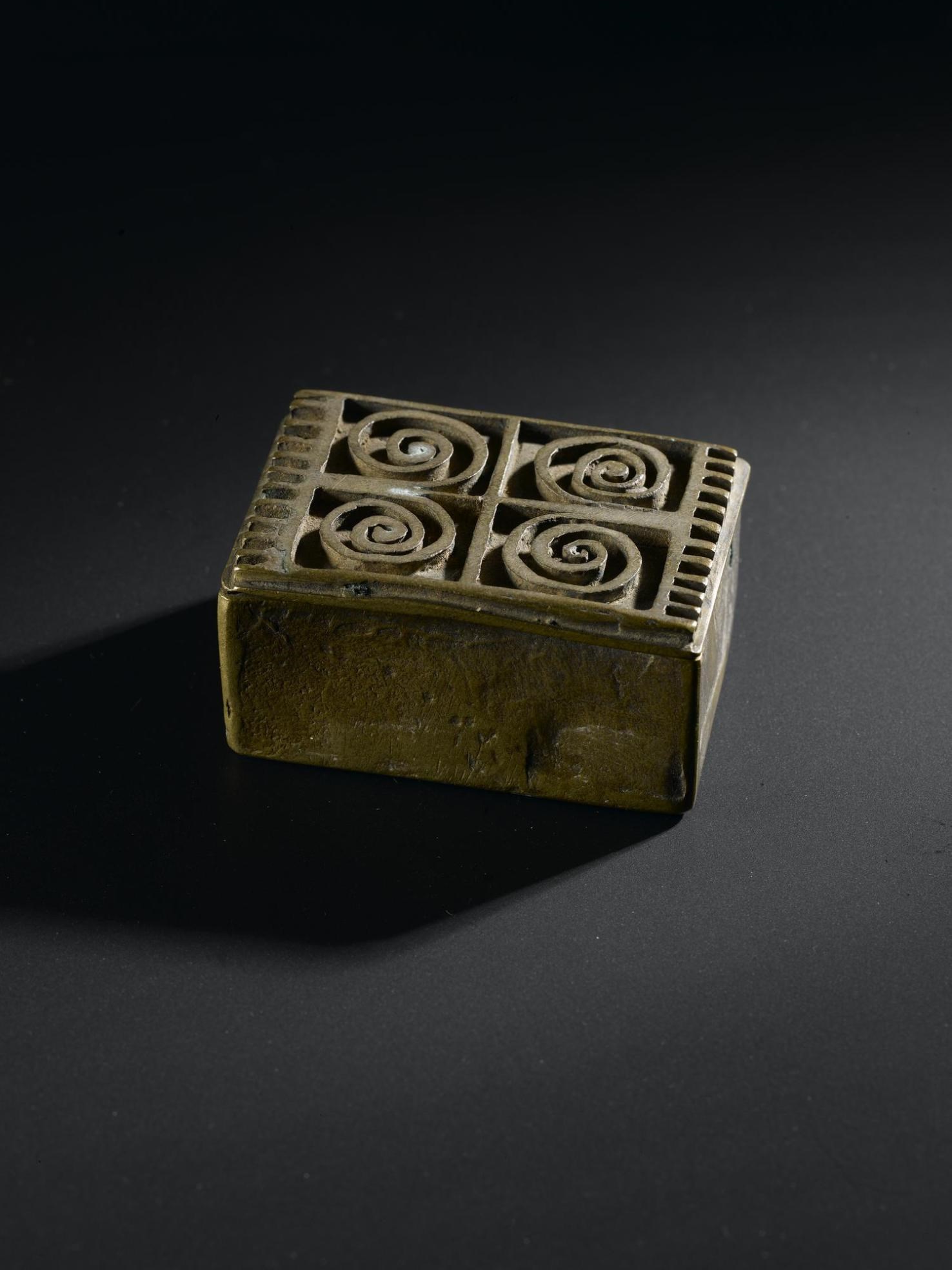 Brass box for holding gold-dust, rectangular with lid decorated with relief scrolls, produced by lost-wax casting: West Africa, Ghana, Asante, late 19th to early 20th century