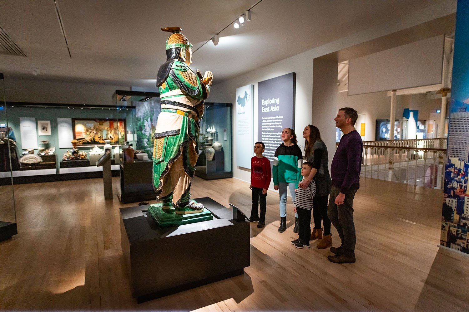 A family looking up at a statue in the Exploring East Asia gallery.