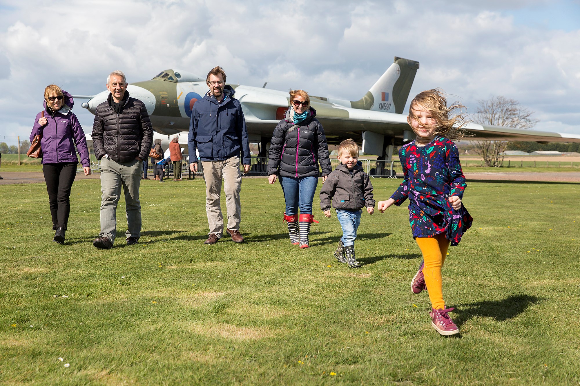 A family of six walking across a grassy field away from a large aircraft