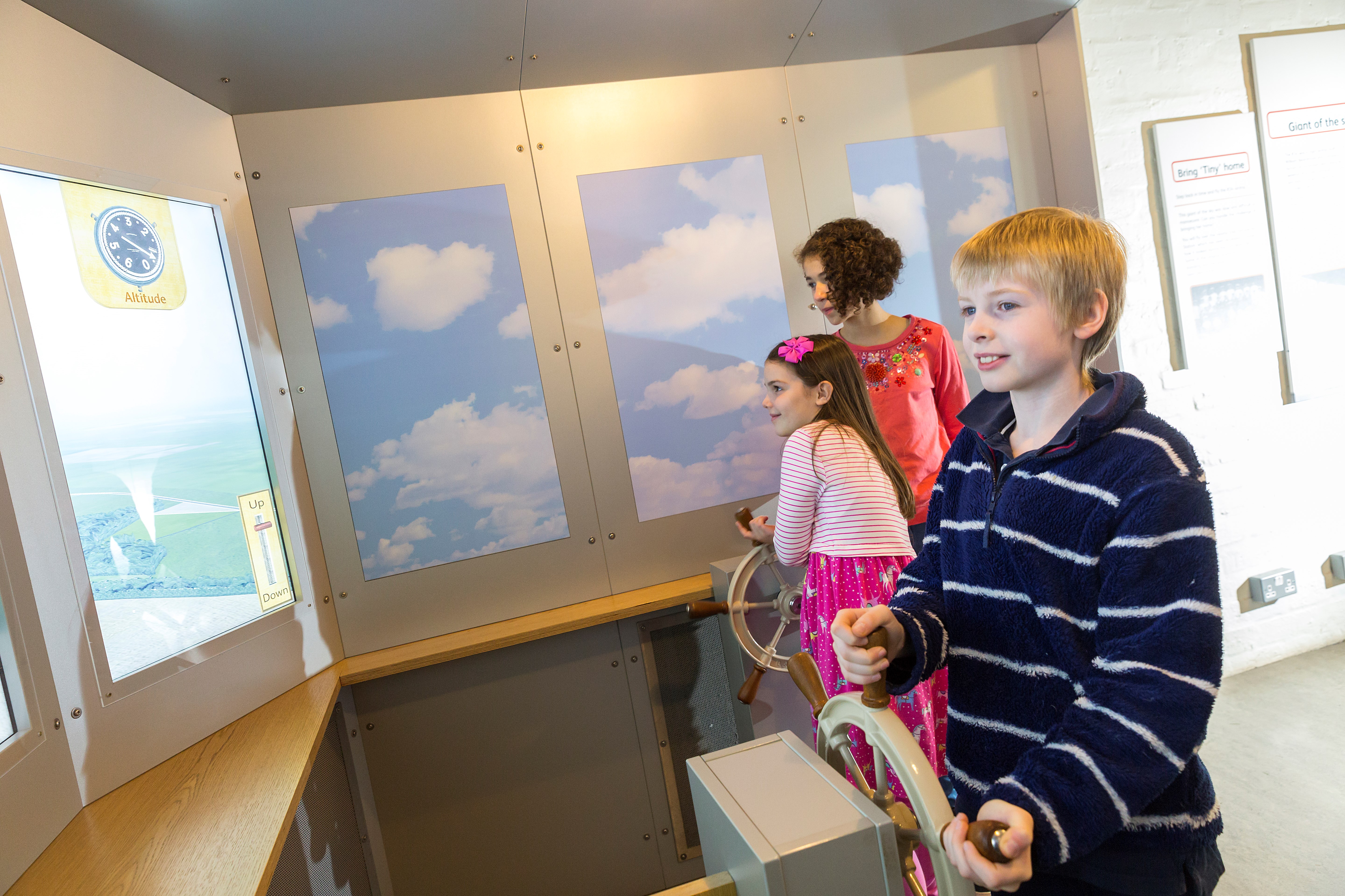 Three children interacting with a display at the National Museum of Flight
