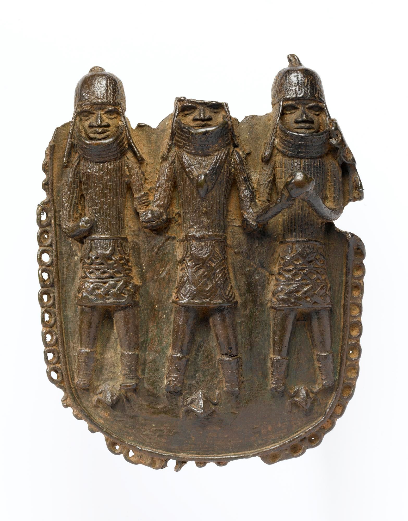 Bronze pendant chipped around the edges. Three figures in armour and heavy helmets stand side by side. The top of the middle figure's head is broken off.