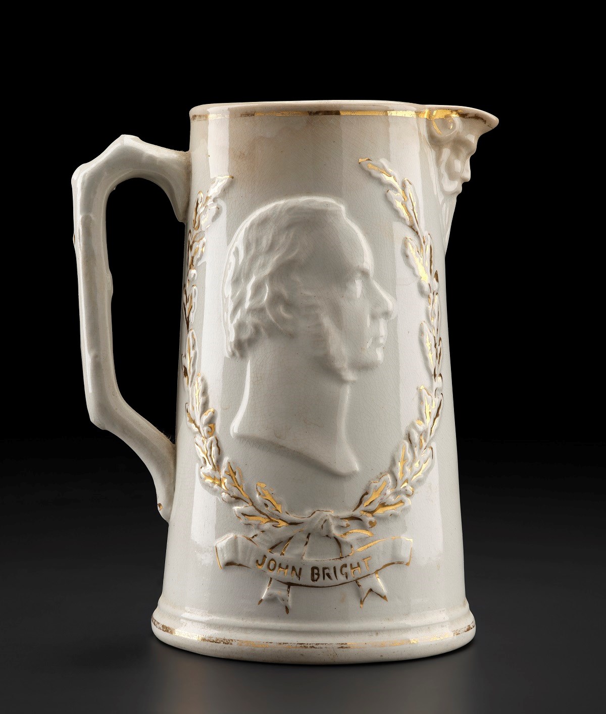 Tall white jug with thin handle on the left side and small spout facing right. Decorated with bust of a man facing right with bushy facial hair.