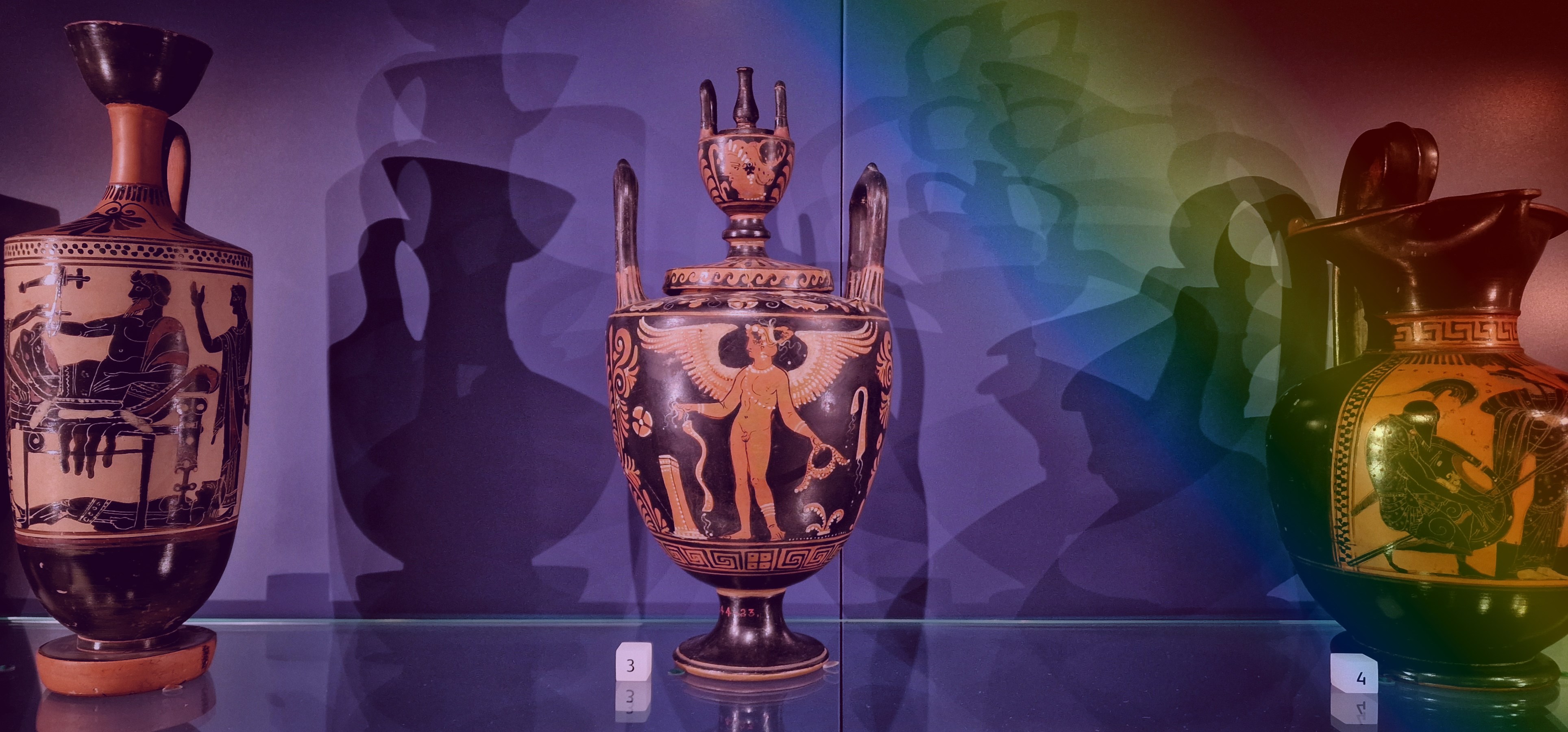 Urn depicting a naked human figure with wings. Image has a transparent rainbow overlay.