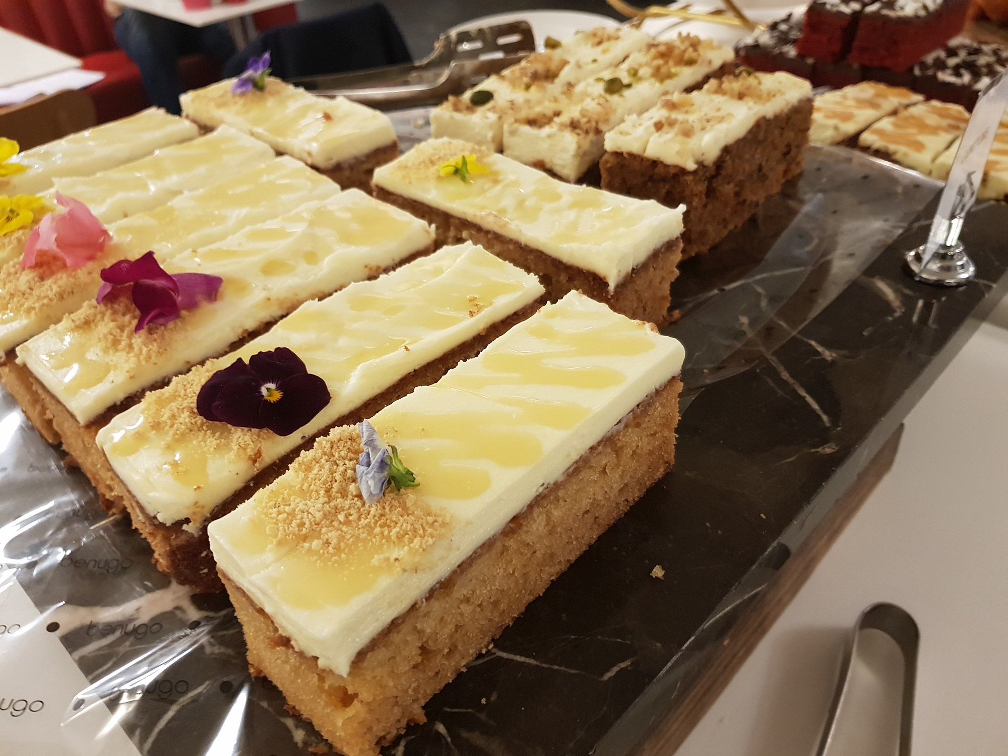 Rectangles of yellow cake with white icing and floral decorations