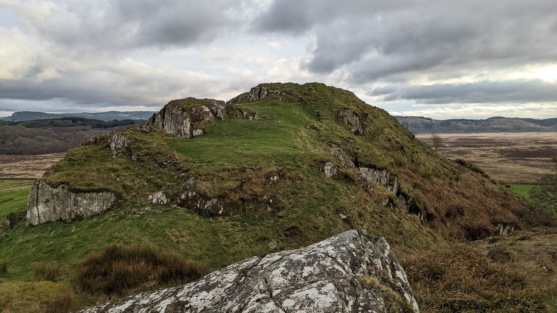 A rocky crag and a view to the old Citiadel at Dunadd hillfort.