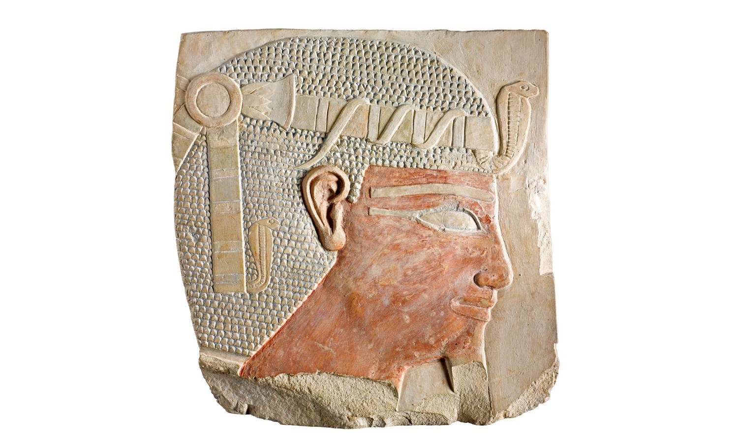 Relief on limestone showing the crowned head of a male Egyptian ruler. His hair is densely patterned with small triangles, and his crown has a cobra at the front.