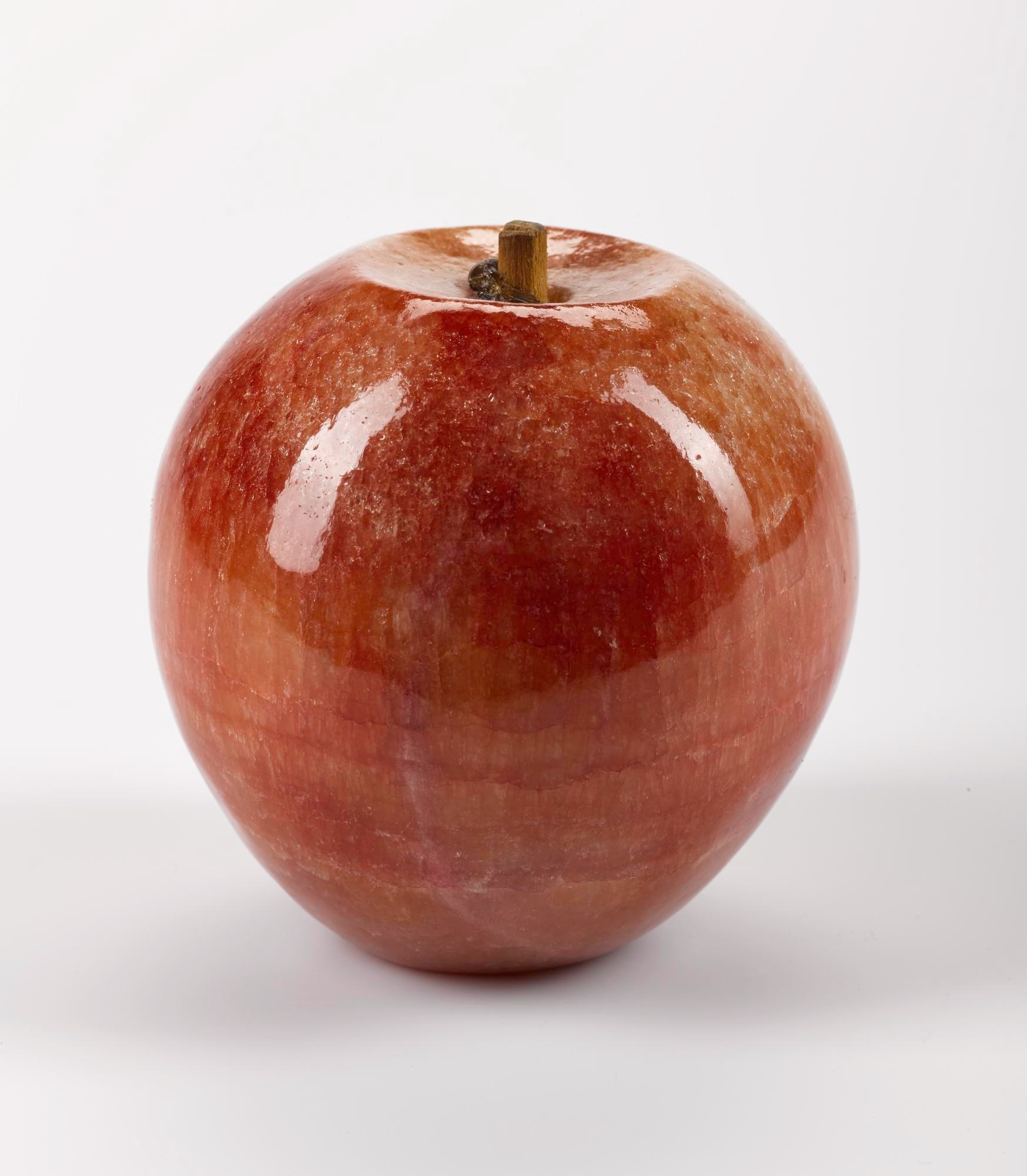 A very shiny red apple, so perfect it almost looks fake, against a white background.