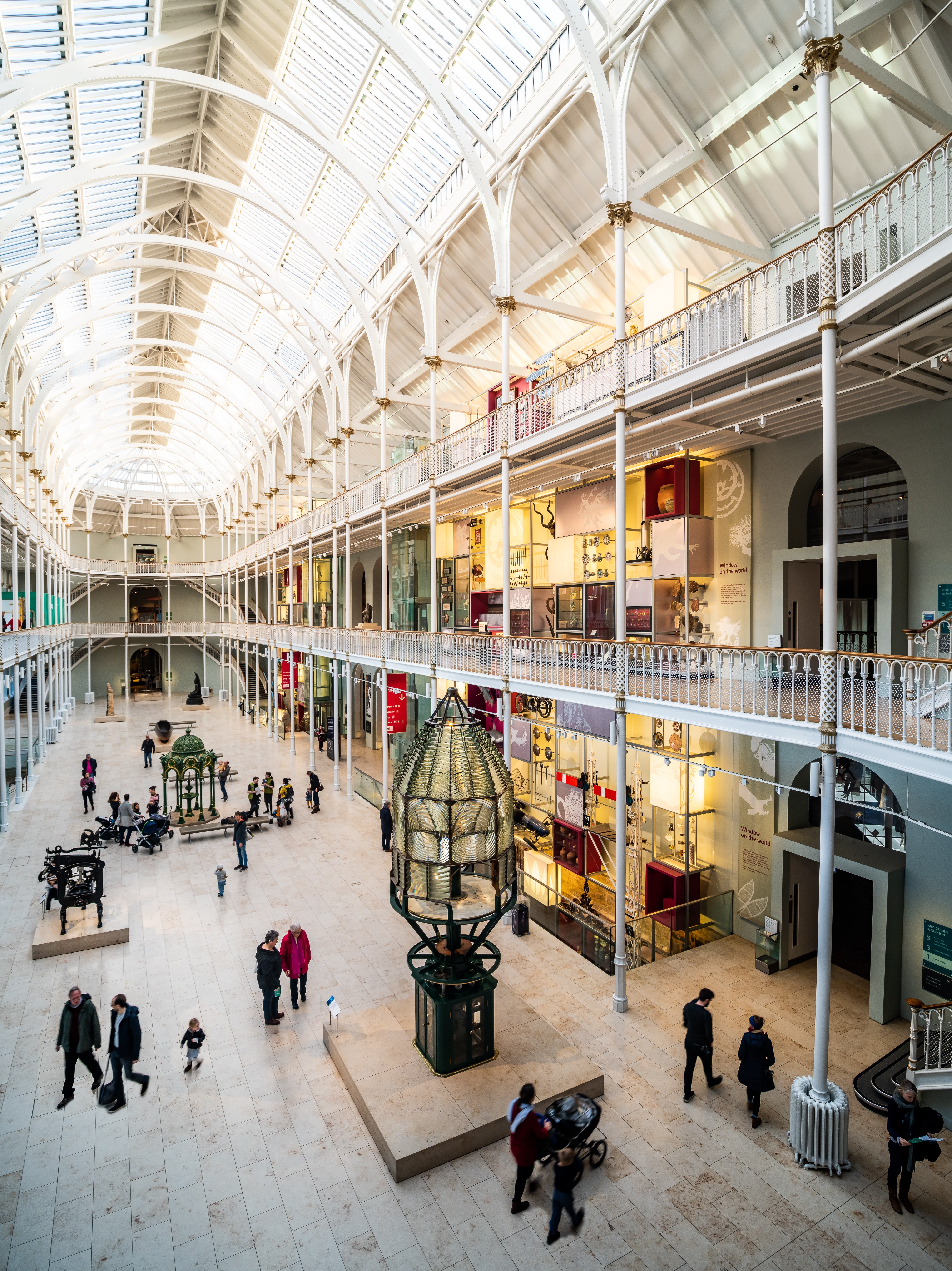 Visitors walk through the Grand Gallery on a sunny day at the National Museum of Scotland, exploring objects within the Window on the World gallery.