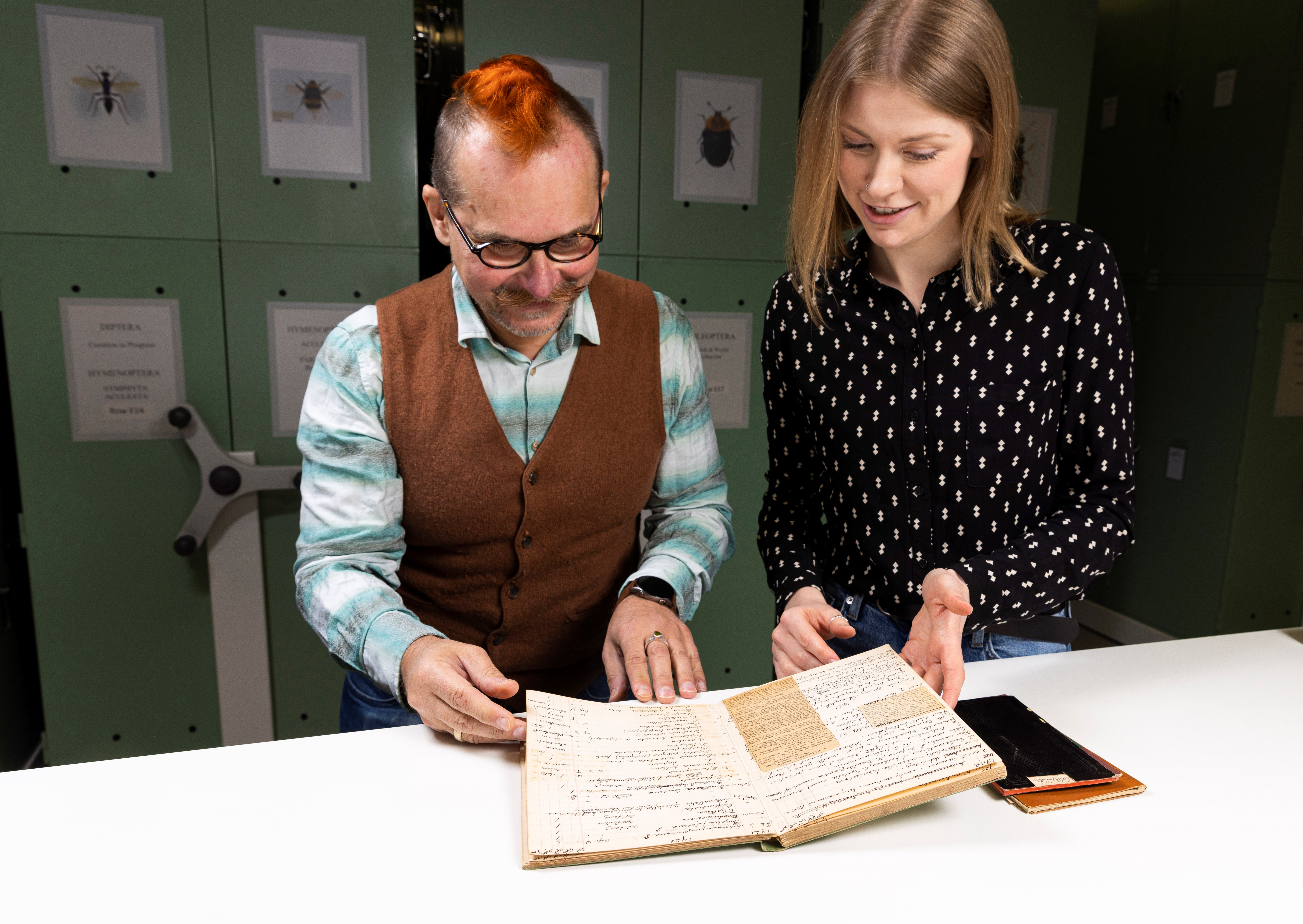 Two entomologists examine records of collections data.