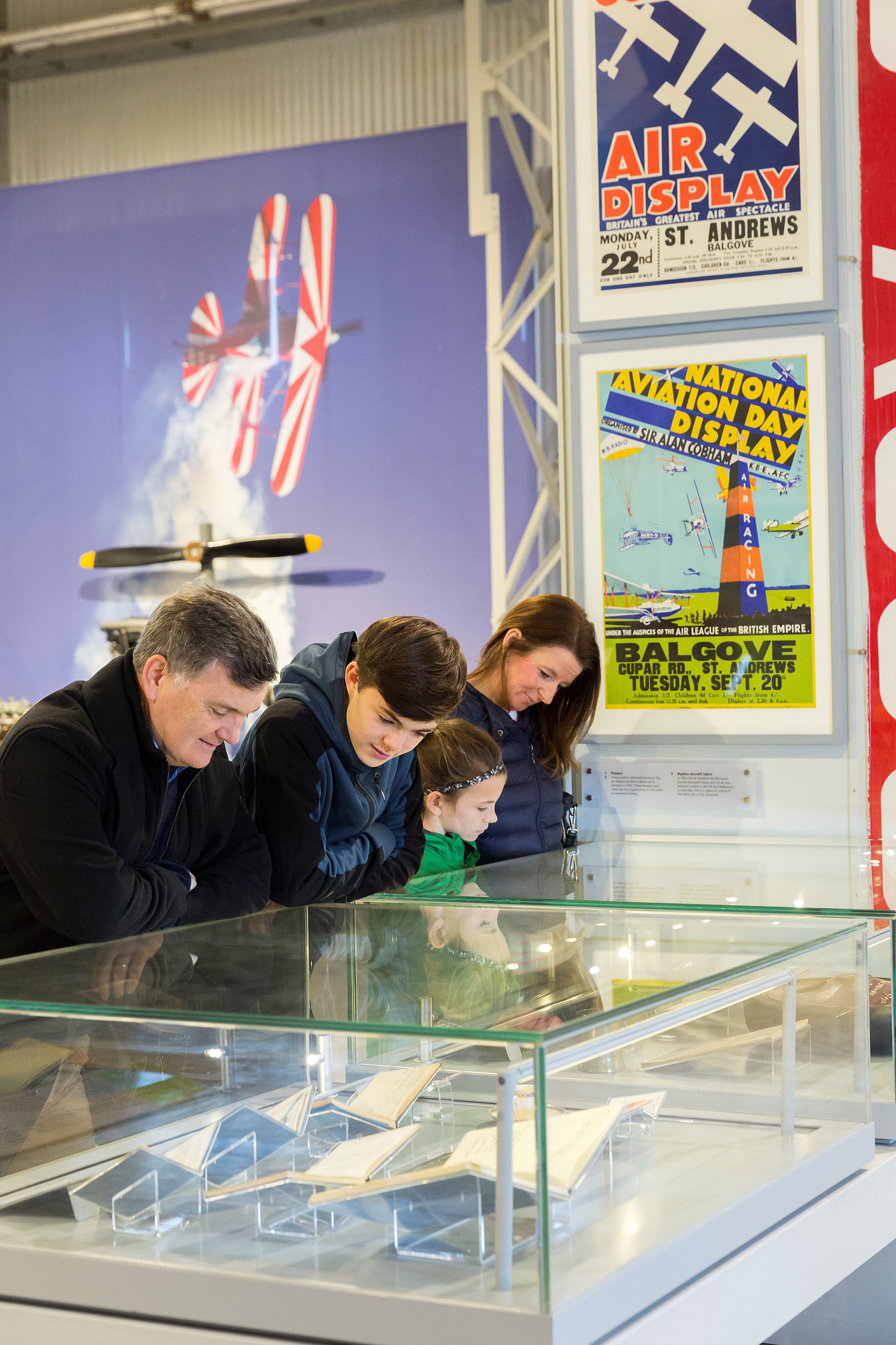 Four visitors look into lit glass case.