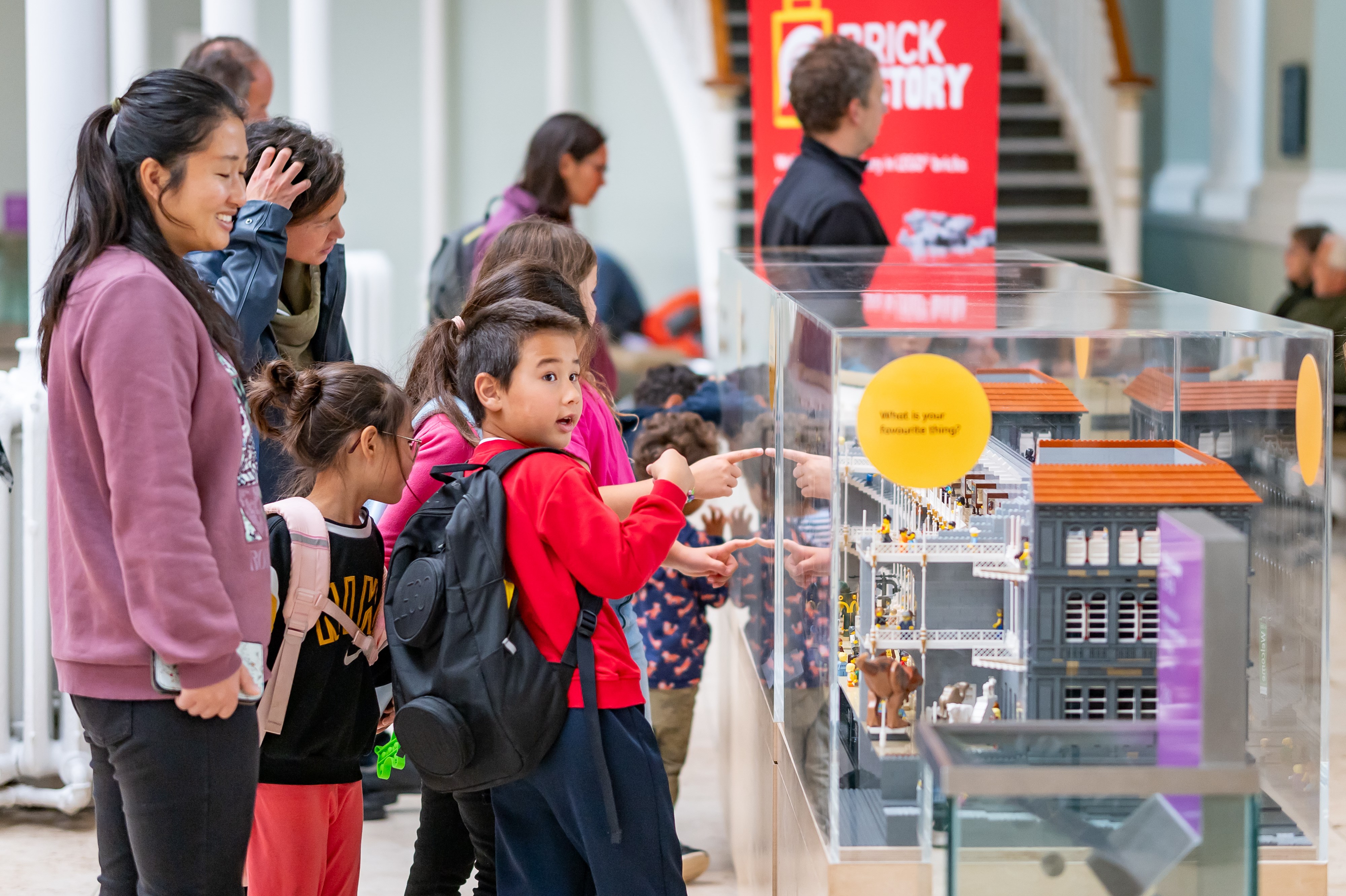 A child is pointing at a display case at the National Museum of Scotland, and looks excited.