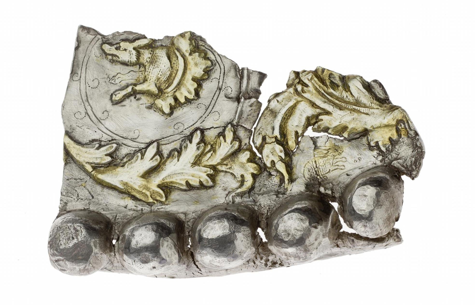 Silver fragment with jagged top edges and bulbous parts at the bottom with decorative gold leaves.
