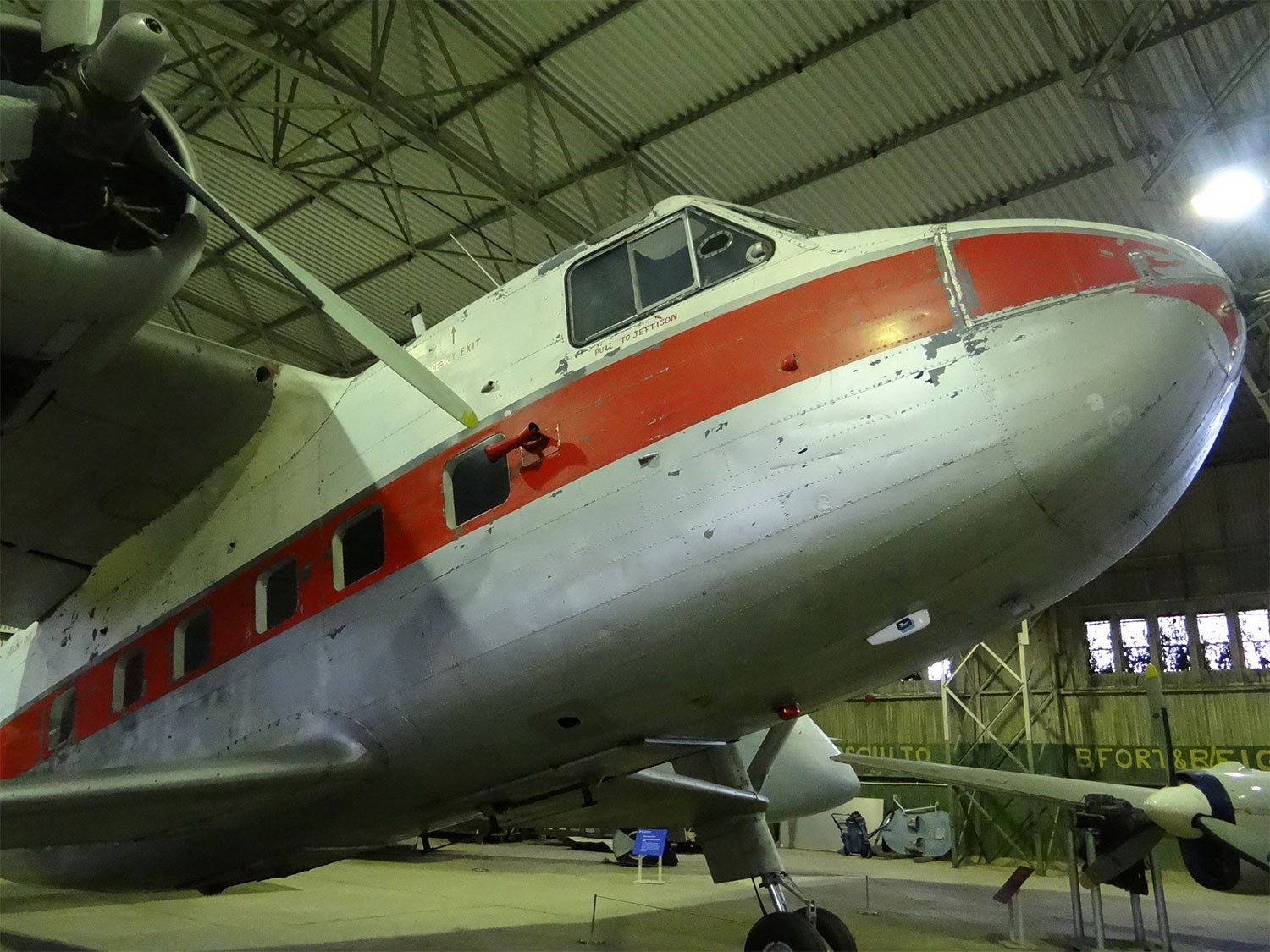 A white Scottish Aviation Twin Pioneer aircraft with a red stripe parked in a large hangar.