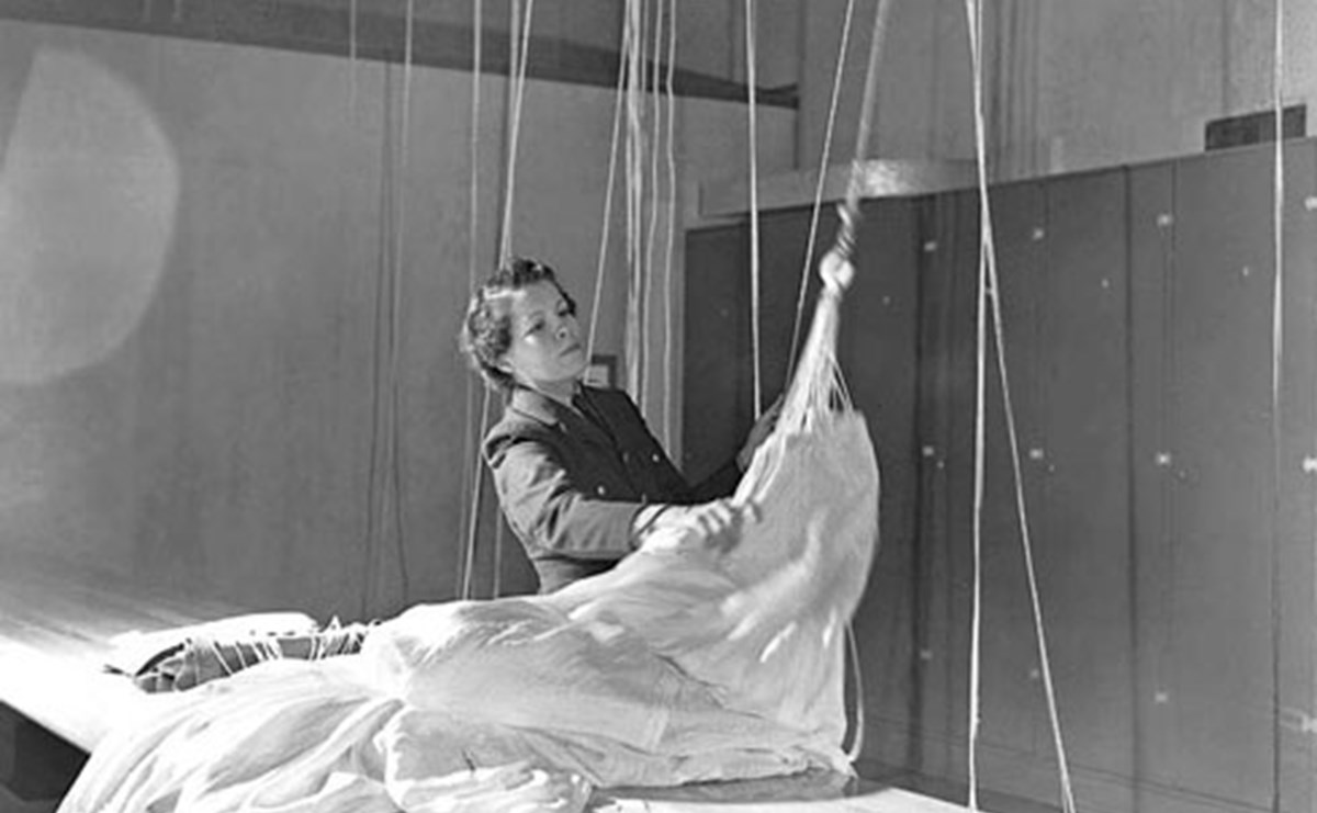 A woman packing up a parachute in a store
