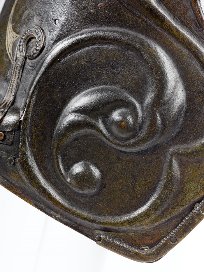 Scrolling repousse decoration on the pony cap