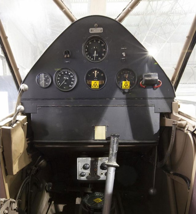 Inside the cockpit of a Puss Moth aircraft. There are five dials and two switches on the dashboard.