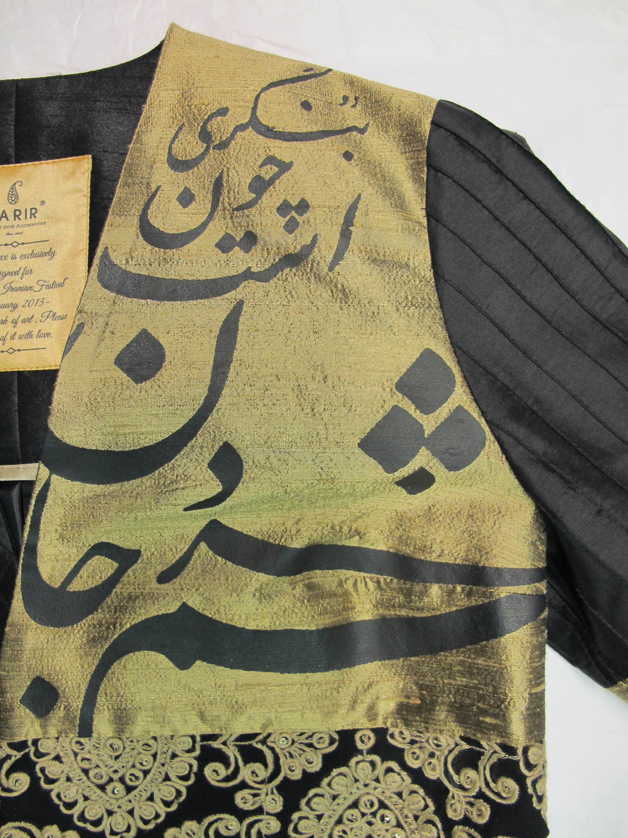 Black coat: detail of the screen-printed calligraphy on the left shoulder with words from a poem by Ferdowsi.