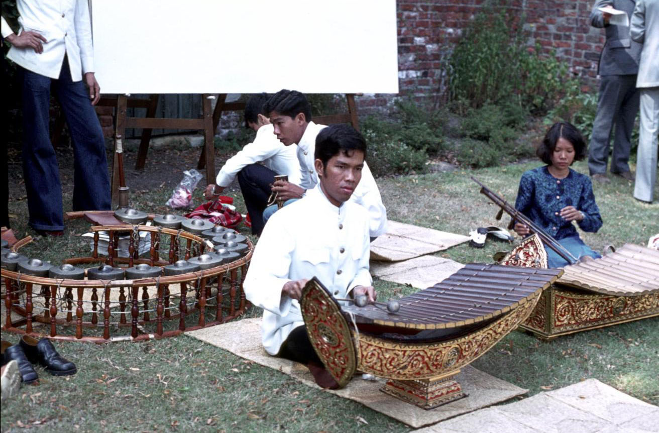Slide of a concert in a garden, in view are a xylophone player, a spike fiddle player and a circle of gongs: Thailand, 1972, photographed by Jean Jenkins.