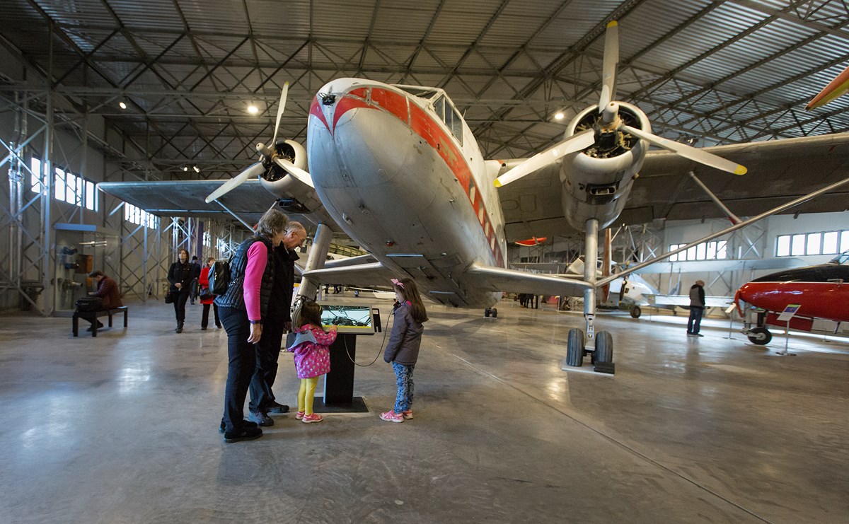 Family looks at a screen under the nose of an airplane in a hangar