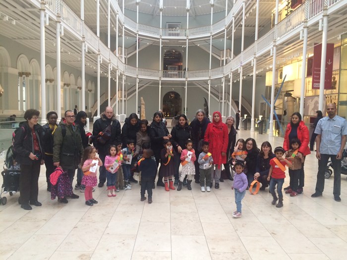 A group of families with young children stand in the main gallery of the National Museum of Scotland