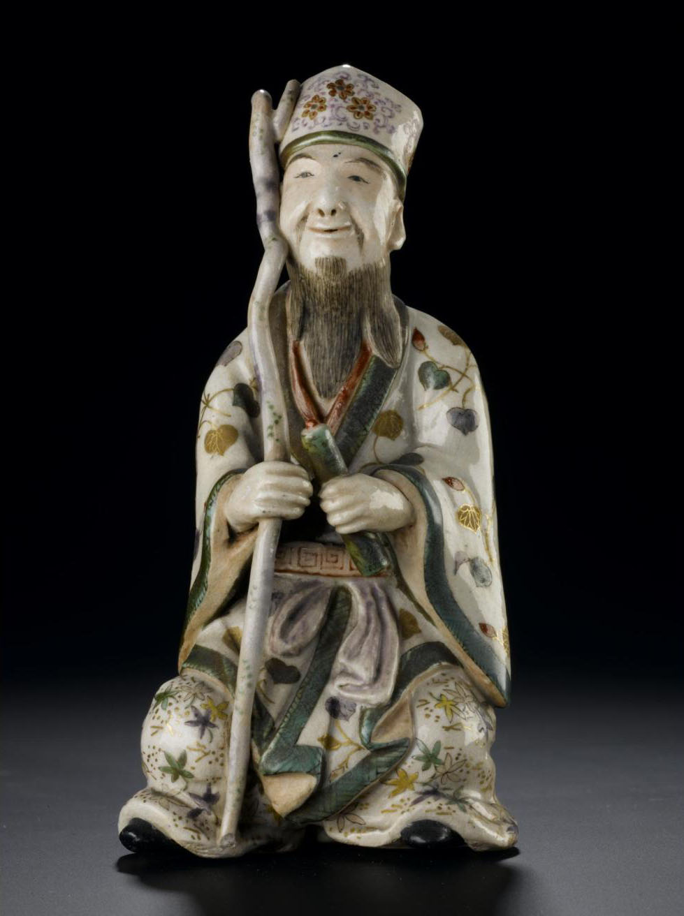Figure of Jurojin seated on a small rock, from a set representing the Seven Gods of Good Fortune: Japan, Satsuma, 19th century. On display in the Window on the World, National Museum of Scotland. 