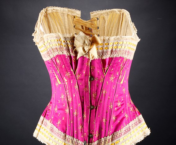 A pink corset with cream and gold lace trim