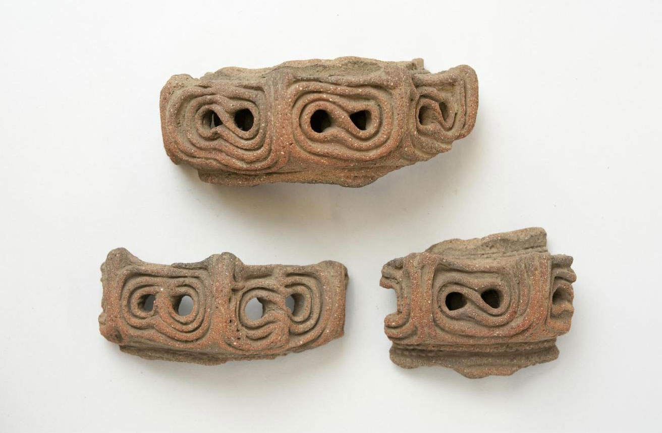 Moulded ornament for vessel rim in three pieces, of red pottery, hollow and perforated: Japan, Musashi province, Negishi shell-mound, Jomon period.
