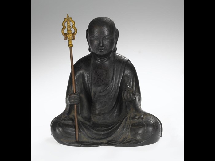 Figure in bronze of the bodhisattva Jizo, in the form of Keiki Jizo, holding in his right hand a ringed staff (shakujo), and in the left hand the jewel (cintamani), seated dressed in the robes of a Buddhist monk: Kamakura, Japan, Kei School, 14th century.