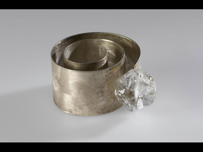 Finger-ring entitled Chikyūjō no hyōga ga tokenai yō ni inotte (Praying the Glaciers on Earth Won't Melt), made of a loosely coiled band of broad, flat silver with an irregularly-cut piece of clear glass: Japan, Osaka, by Mitsushima Kazuko, 1997. On display in the Inspired by Nature gallery at the National Museum of Scotland.