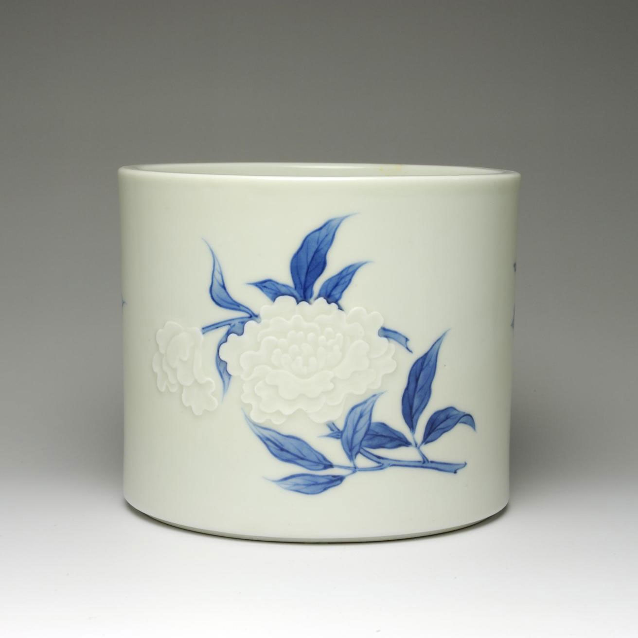Straight-sided porcelain water jar (mizusashi) for tea ceremony, with low relief and underglaze blue decoration of peonies: Japan, c1890s.