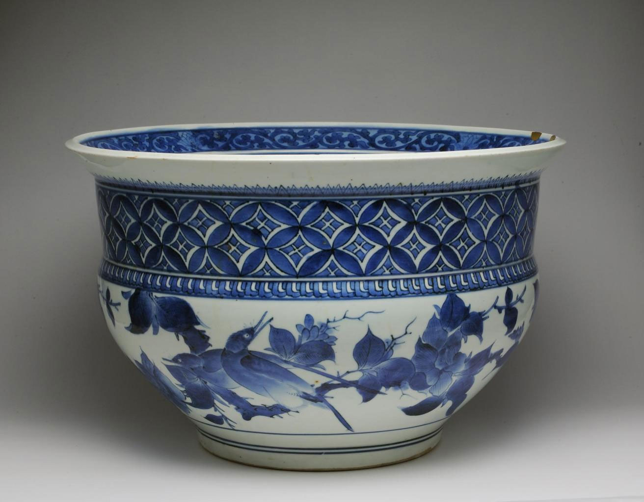 Large fish-bowl of porcelain with underglaze blue decoration of birds on branches and a diamond lozenge pattern above, with gold lacquer repairs to rim: Japan, 1660-80.