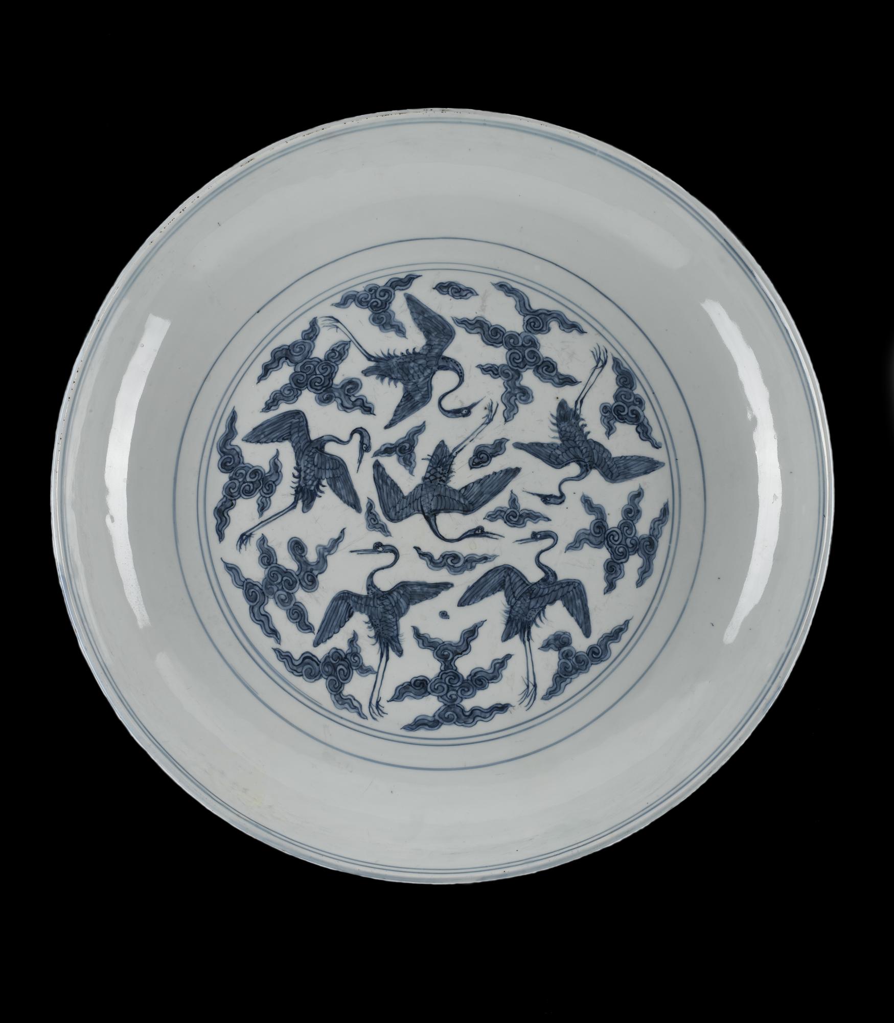 Circular porcelain dish decorated in underglaze blue with a design of cranes flying among cloud scrolls: Chinese, Ming dynasty, Jiajing reign, 1522-1566.