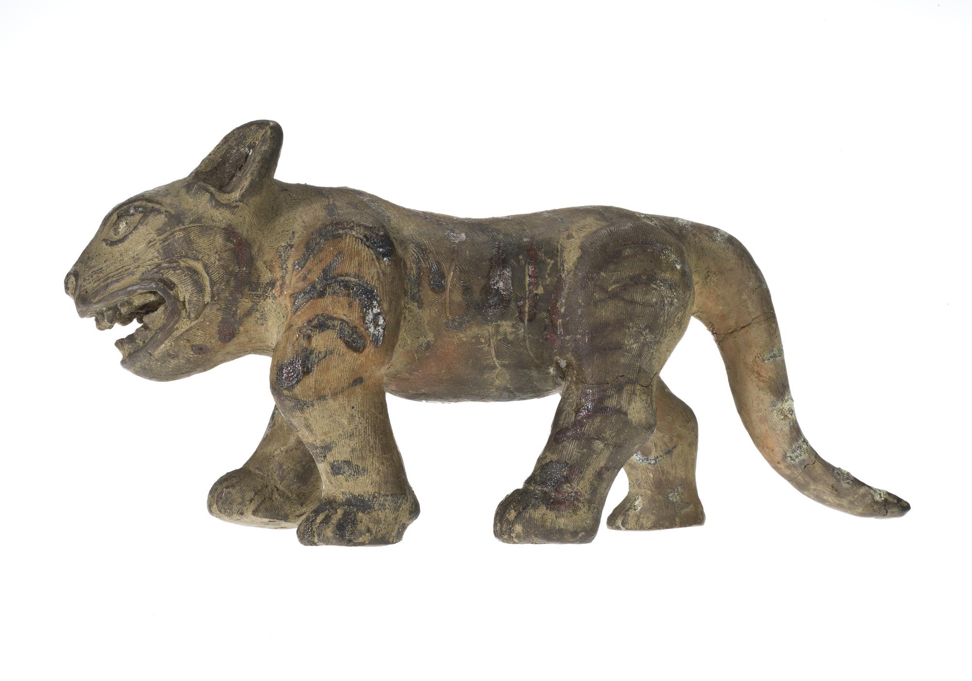 Figure of a tiger in hard reddish pottery, decorated with combed surface markings and red and green glazes: China, Liang dynasty, 502-556 AD.