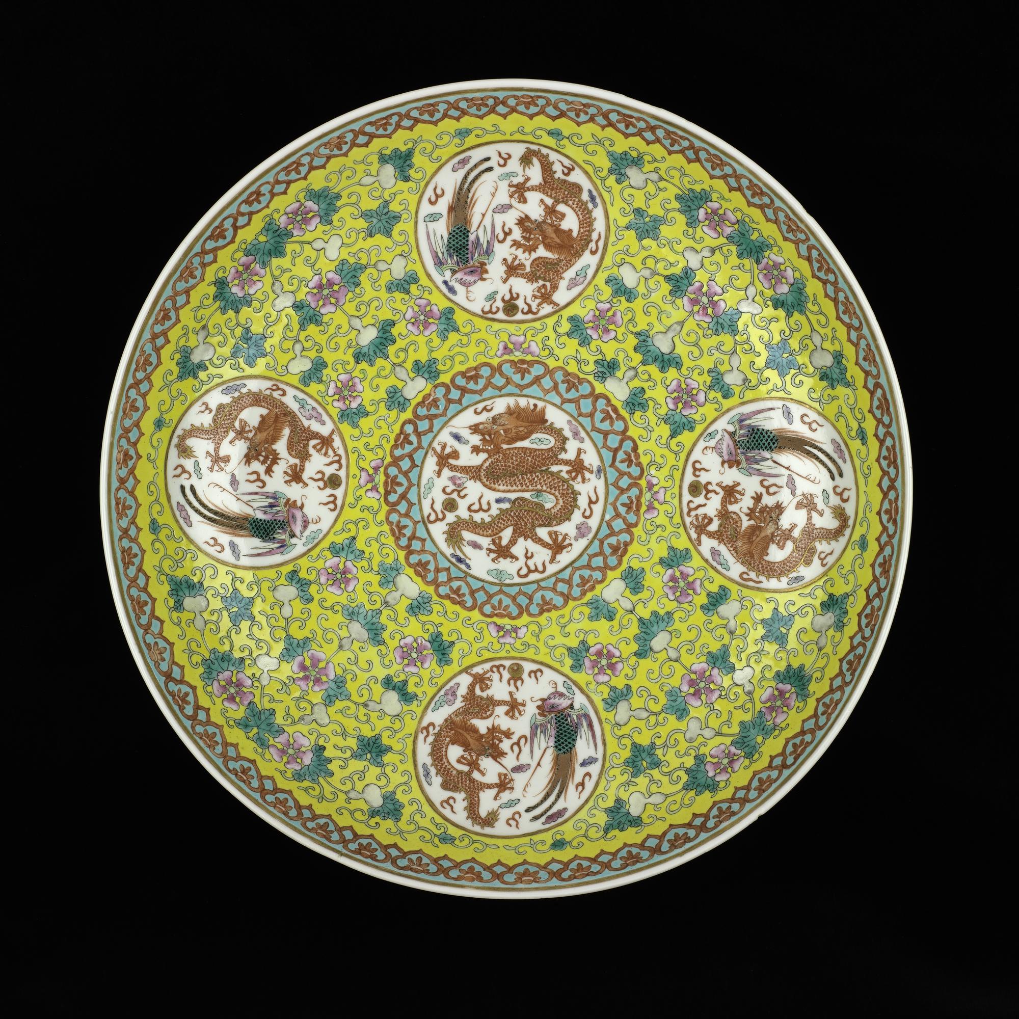 Circular porcelain dish, decorated in overglaze enamels on a yellow ground with a central roundel containing a red dragon and pearl, surrounded by four roundels each containing a red dragon and a phoenix, with a reign mark on the base: China, Qing Dynasty, Qianlong reign, 1736-1795 AD. 