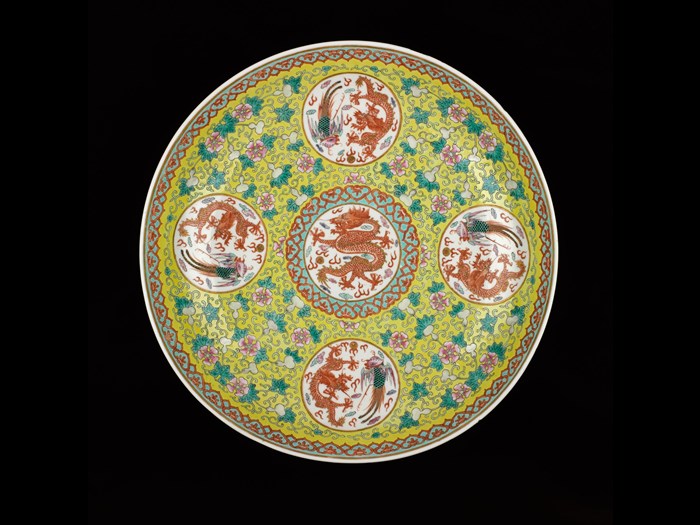Circular porcelain dish, decorated in overglaze enamels on a yellow ground with a central roundel containing a red dragon and pearl, surrounded by four roundels each containing a red dragon and a phoenix, with a reign mark on the base: China, Qing Dynasty, Qianlong reign, 1736-1795 AD. 