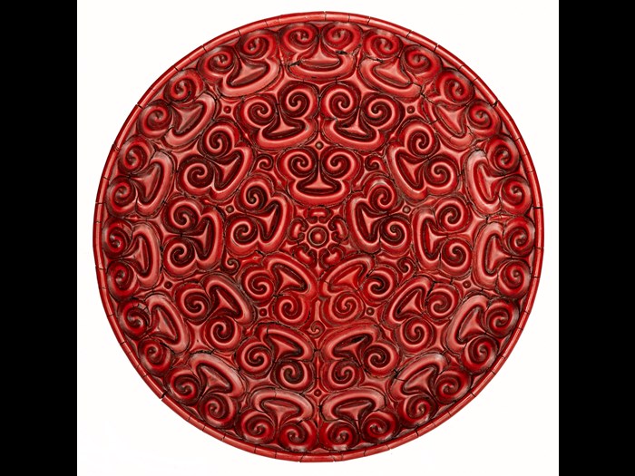 Circular dish of red lacquered wood carved on upper surface with three bands of spectacle-shaped designs surrounding a centre of petals and arrowhead patterns: China, Yuan dynasty, 14th century.