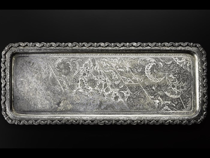 Rectangular tray of silver with an asymmetrical pattern depicting a landscape with trees and cranes overlaid with fine curved leaves and flowers, with an embossed edge, hallmarked on the reverse, Iran, Isfahan, 1920s-1940s, acc. no V.2015.64