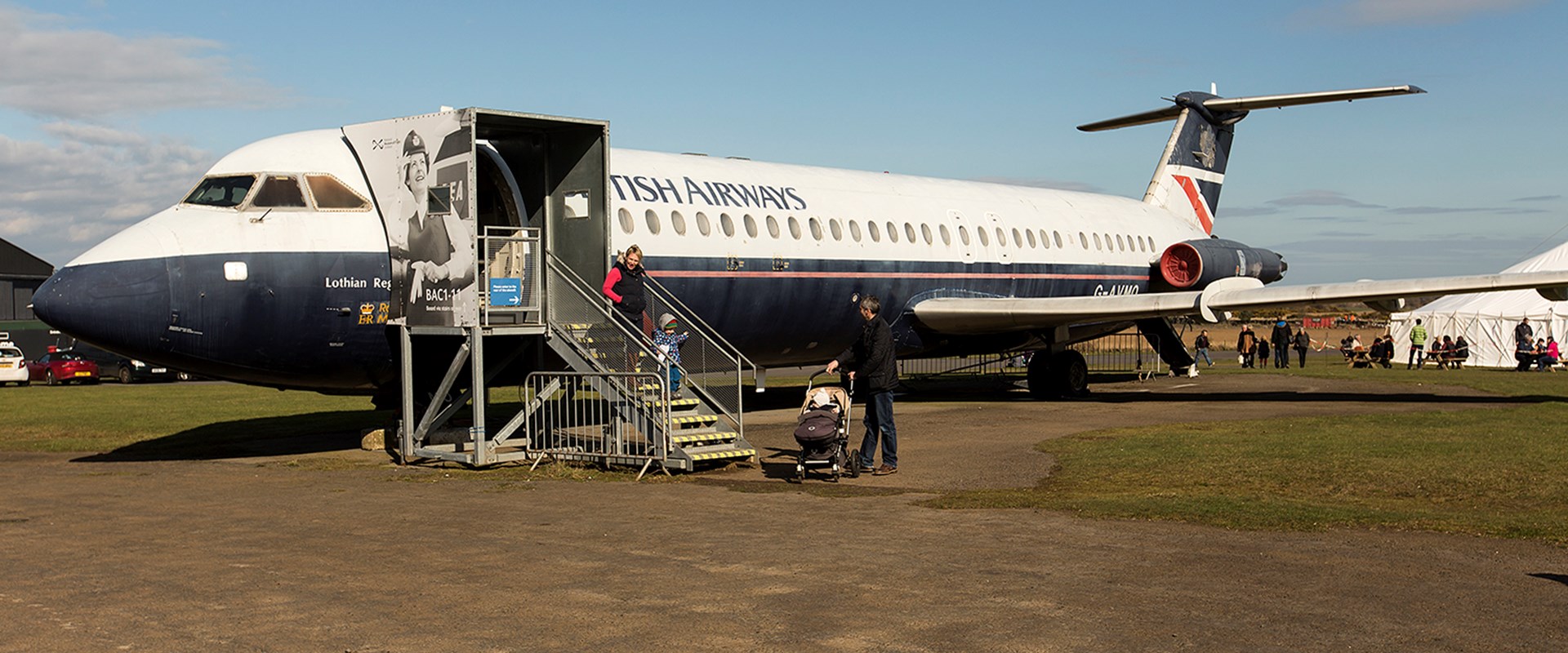 A family walking down the steps of a plane in an airfield